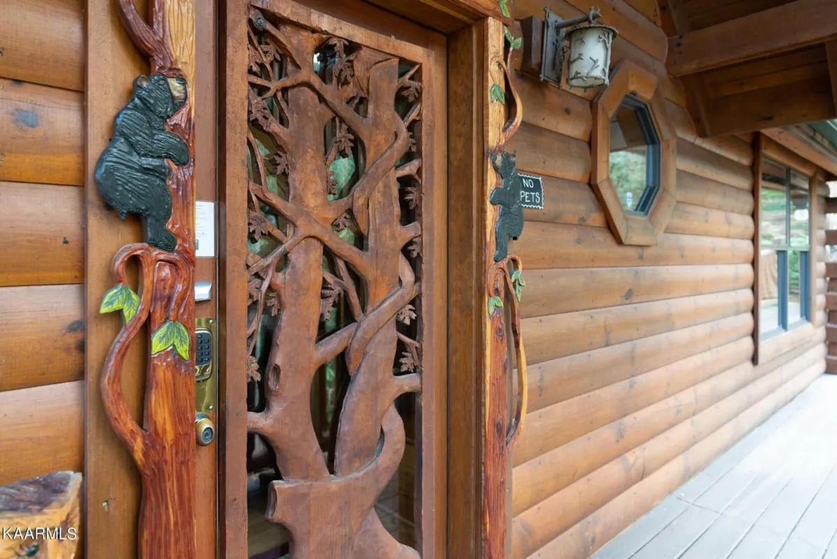 Focusing on the intricately carved wooden front door featuring a bear figure and rustic textures, this welcoming entrance sets the tone for a cozy mountain getaway and hints at the personal, private experience awaiting inside.