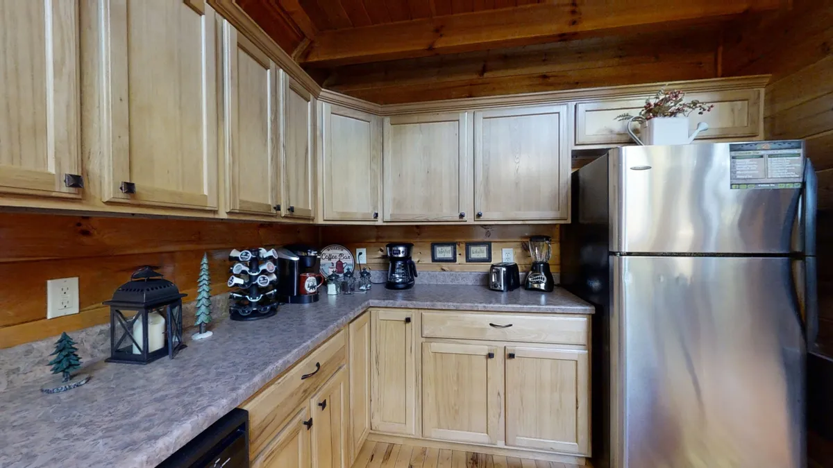 This image features a warm, inviting kitchen with wooden cabinets, modern appliances, and tasteful countertop decor. The space is designed to be both functional and social, encouraging groups to cook, share meals, and enjoy each other's company. The layout allows for easy movement and interaction, reflecting the cabin's communal spirit.