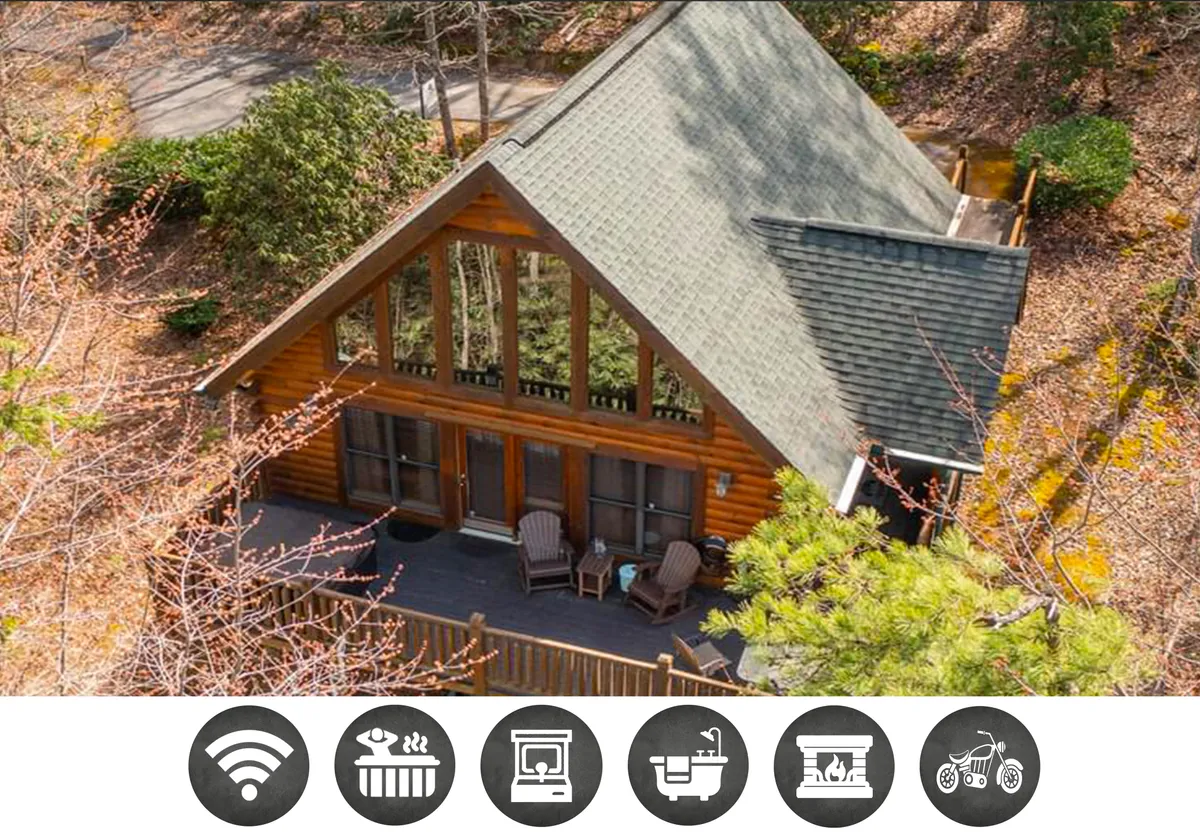 The image showcases a charming log cabin nestled among lush Smoky Mountain trees, featuring expansive windows and a spacious deck with inviting chairs—all set in a tranquil, semi-private setting ideal for relaxation and taking in sunset views.