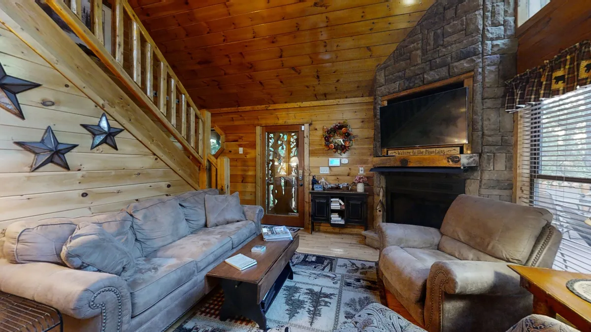 The cozy living room showcases a sofa by a double-sided stone fireplace, wooden staircase, and decorative stars, all wrapped in a comfortable, inviting ambiance ideal for relaxing evenings after a day of adventure.