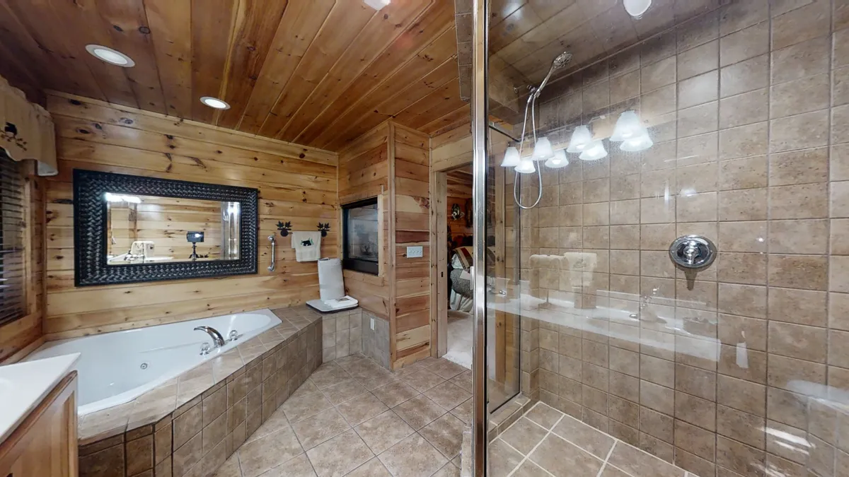 This image features a sauna-style space with wooden paneling, a jacuzzi tub, a shower area, and a framed mirror. The tranquil mood and spa-like details evoke relaxation and self-care, providing a glimpse of the private walk-in sauna experience available in the loft.